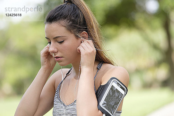 Junge Frau stellt Kopfhörer beim Sport ein
