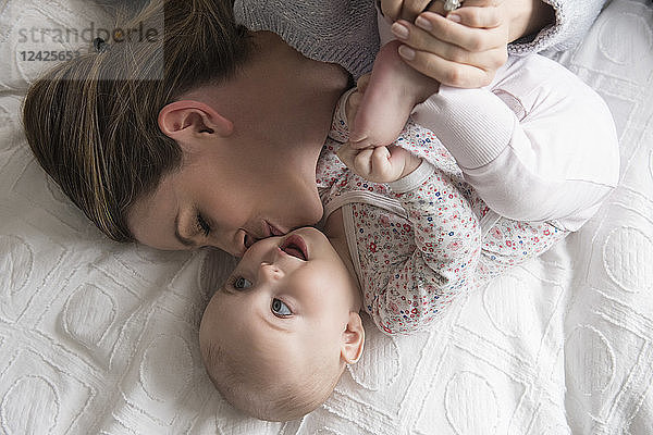 Mutter küsst liebevoll ihr kleines Mädchen (18-23 Monate)