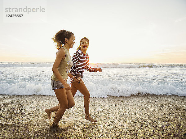 Mutter und Tochter joggen am Strand