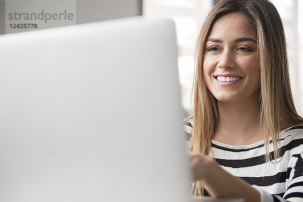 Lächelnde junge Frau am Laptop