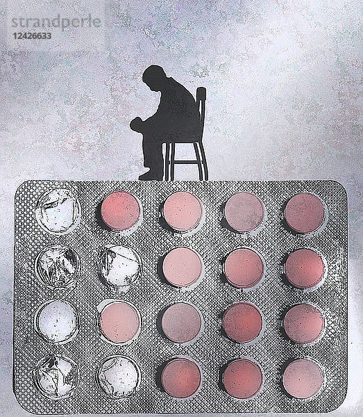 Depressiver Mann sitzt auf einer Pillenblisterpackung