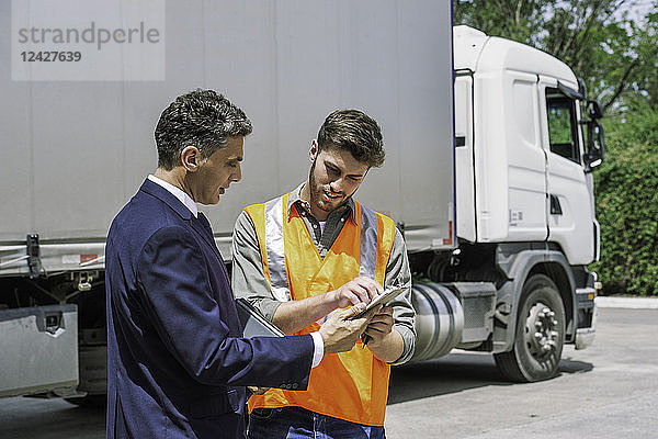 Arbeiter und Geschäftsmann diskutieren in der Nähe eines Lastwagens