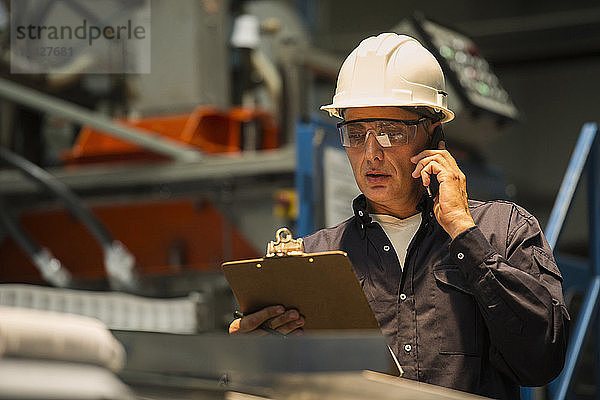 Fabrikarbeiter mit Mobiltelefon in der Fabrik