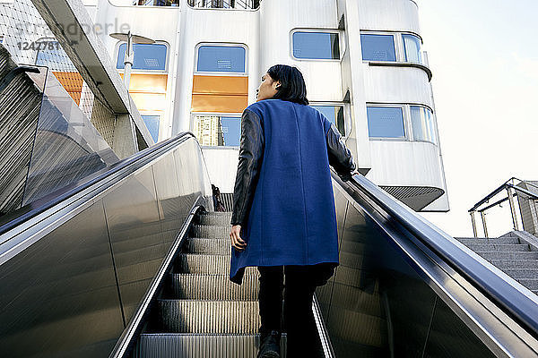 Frau auf Rolltreppe stehend