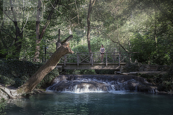 Einsame Frau steht auf einem Steg über einem Fluss im Wald  Monasterio de Piedra  Provinz Zaragoza  Spanien