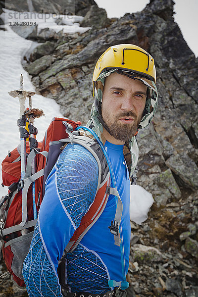 Porträt eines Bergsteigers mit Sicherheitshelm  der in die Kamera schaut