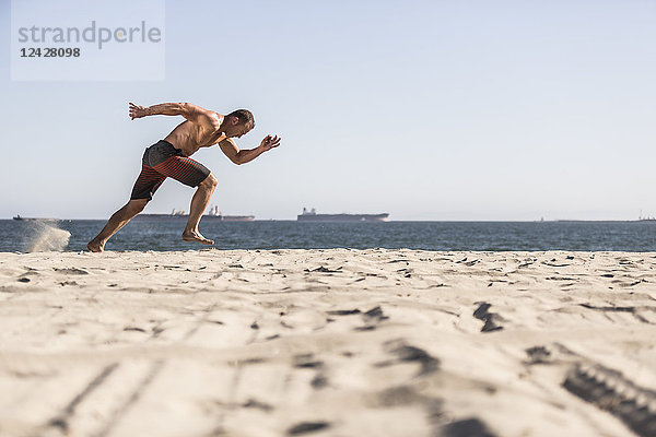 Seitenansicht Schuss von hemdsärmeligen Mann sprinten beim Training am Strand