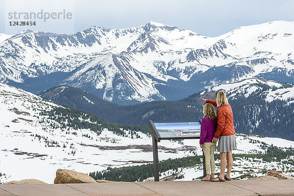 Mutter und Tochter stehen in einer wunderschönen Naturlandschaft mit schneebedeckten Bergen an der Trailridge Road mit Blick auf die Never Summer Range  Rocky Mountain National Park  Estes Park  Colorado  USA