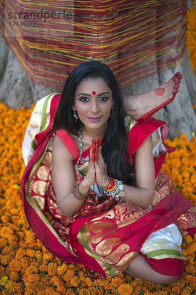 Vorderansicht einer Frau in traditioneller indischer Kleidung  die Yoga macht und in die Kamera schaut