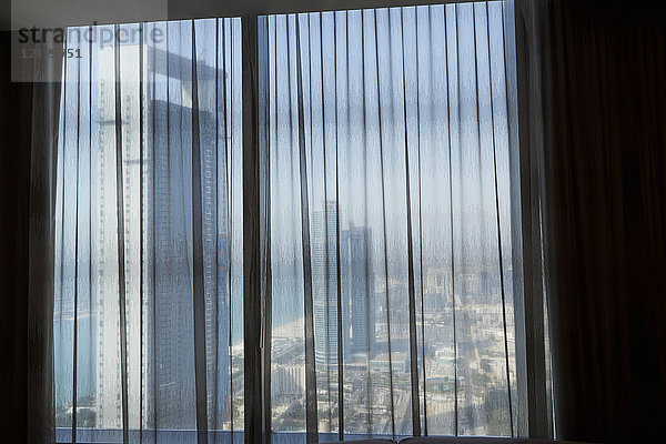 Blick auf Wolkenkratzer von Abu Dhabi durch einen Vorhang im Fenster  Vereinigte Arabische Emirate