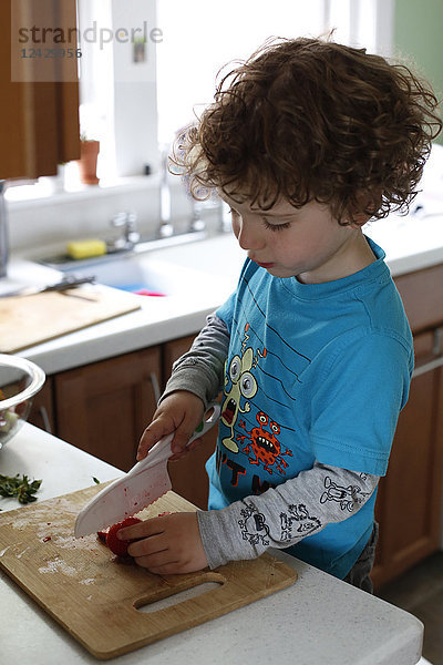 Seitenansicht eines Jungen  der in der Küche Erdbeeren schneidet