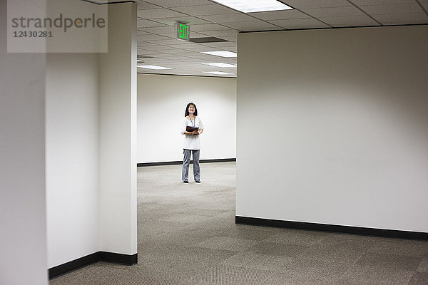 Eine asiatische Geschäftsfrau  die allein in ihrem Büro steht.