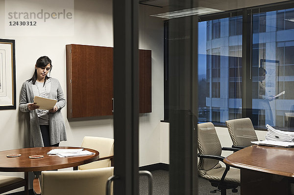 Eine Frau gemischter Rasse  die in einem Büro arbeitet  durch eine Glastür betrachtet.