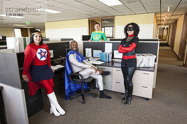 Ein gemischtrassiges Team von Büro-Superhelden ist in ihrem Büro.