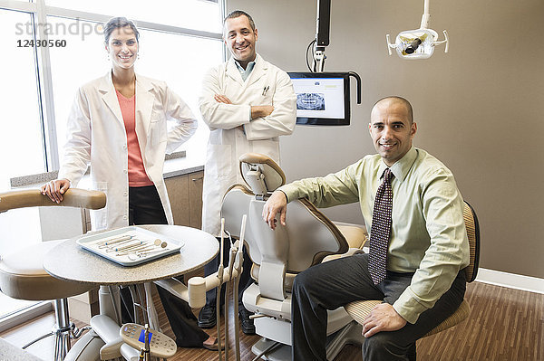 Ein Porträt eines gemischtrassigen Zahnärzteteams in einem zahnärztlichen Untersuchungsraum.