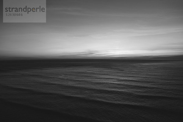 Die Wasseroberfläche des Ozeans in der Abenddämmerung  schwarz-weiß  kräuselt und wellenförmig.