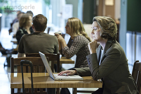 Eine kaukasische Geschäftsfrau  die an einem Laptop-Computer arbeitet  während sie in einem Café sitzt.