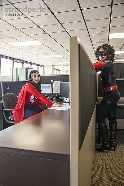 Zwei Frauen sind Superheldinnen in ihrem Büro.