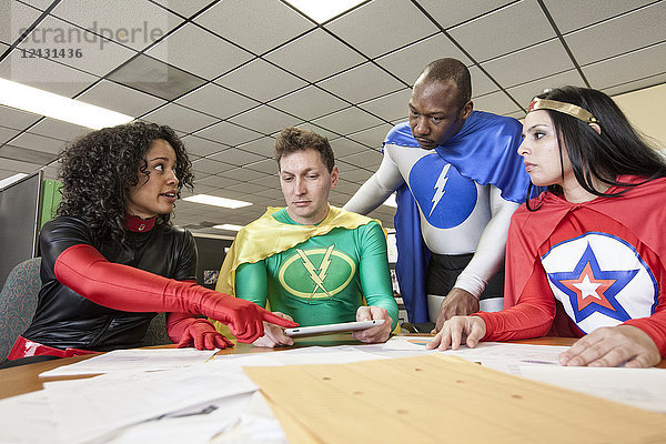 Ein gemischtrassiges Team von Büro-Superhelden ist in ihrem Büro.