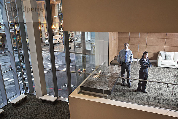 Ein großes Gebäude  Lobby  Blick in ein Büro mit Glaswänden  zwei Geschäftsleute im Gespräch.