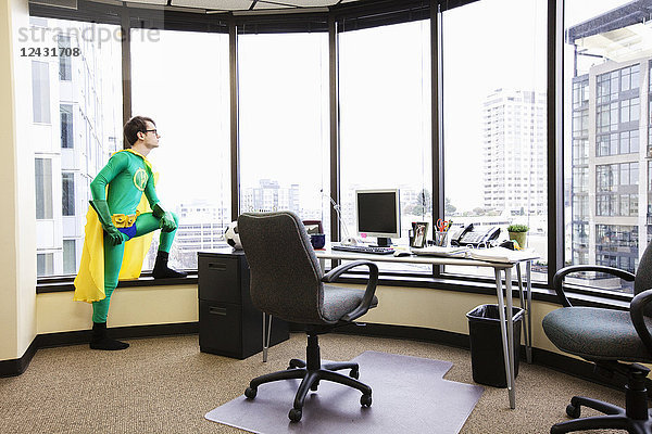 Ein Superheld aus dem Büro eines Weißen steht am Fenster seines Büros und sinniert über seinen nächsten geschäftlichen Schritt.
