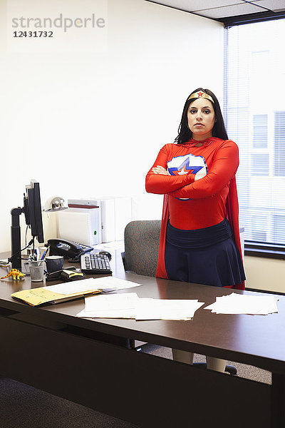 Eine hispanische Geschäftsfrau als Superheldin an ihrem Bürocomputer