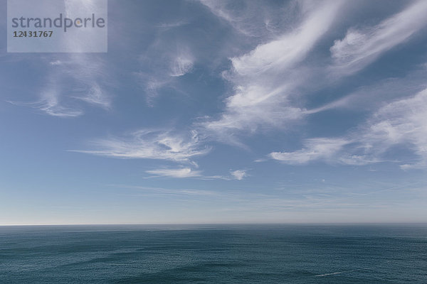 Blick über den Ozean bis zum Horizont  tiefblaues Meer und leichte  vom Wind gewehte Wolkenfetzen am Himmel.