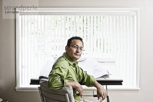 Ein spanischer Mann  der Inhaber einer Landschaftsgestaltungsfirma  sitzt an seinem Design-Schreibtisch im Büro