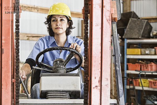 Hispanische Arbeitnehmerin  die einen Gabelstapler in einem Landschaftsbauunternehmen benutzt.