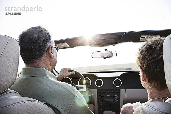 Blick von hinten auf ein älteres Ehepaar in einem Cabrio-Sportwagen  das bei Sonnenuntergang im Osten des Staates Washington  USA  auf einer Autobahn fährt.