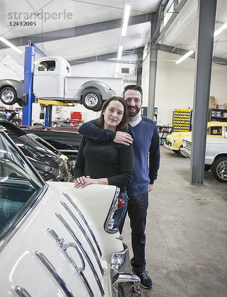 Ein Ehepaar  Mechaniker  die in einer Oldtimer-Autowerkstatt arbeiten. Mann und Frau.