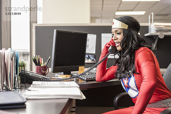 Eine schwarze Büro-Superheldin nimmt in ihrem Büro einen Anruf von einem Kunden entgegen.