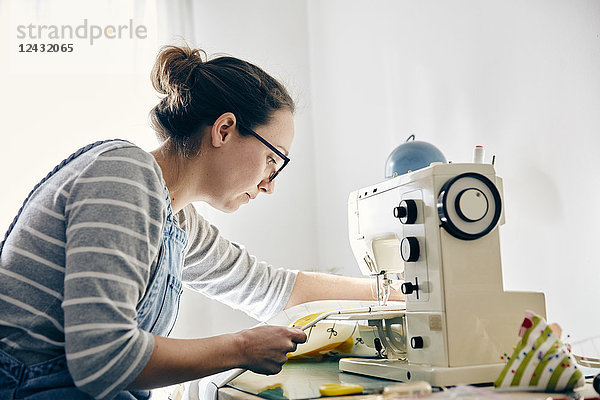 Frau benutzt elektrische Nähmaschine zur Herstellung von Vorhängen