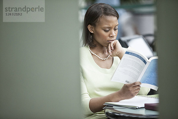 Eine schwarze Geschäftsfrau liest einen Bericht.