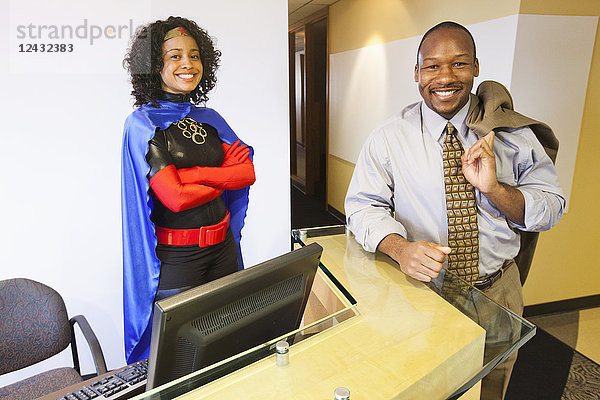 Eine schwarze Geschäftsfrau als Superheldin und ihr schwarzer Geschäftsmann als Partner in ihrem Büro.