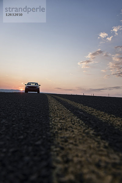 Niedrigwinkelansicht mit Blick auf einen Cabrio-Sportwagen  der bei Sonnenuntergang auf der Straße steht.