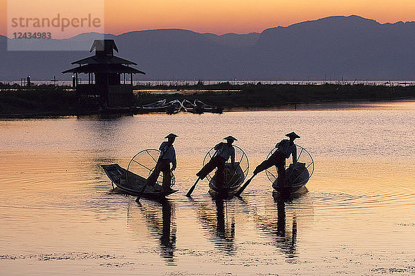 Drei Fischer balancieren bei Sonnenuntergang auf einem Bein auf dem Inle-See  Shan-Staat  Myanmar (Burma)  Asien