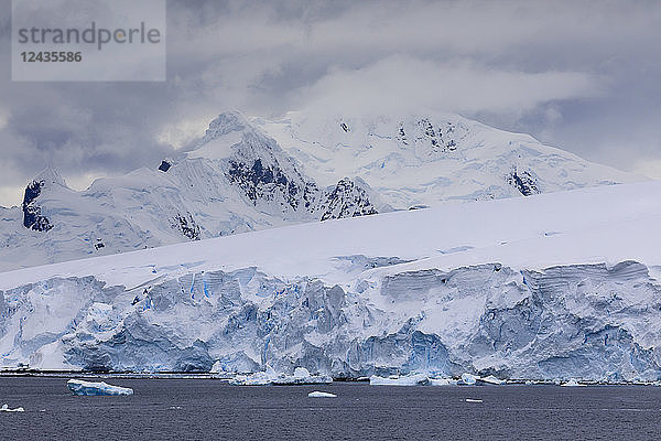 Tiefliegende Wolken über den Bergen und blauen Gletschern der Paradise Bay  Antarktische Halbinsel  Antarktis  Polarregionen