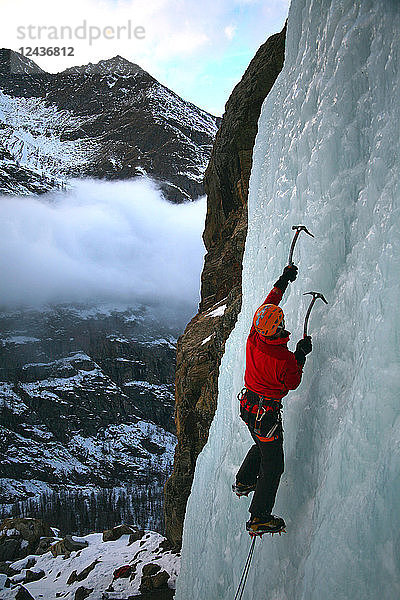 Ein Eiskletterer erklimmt einen gefrorenen Wasserfall in der Nähe von Cogne  oberhalb des Aostatals  Norditalien  Europa