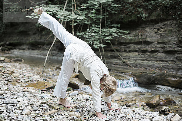 Senior woman doing yoga at brook