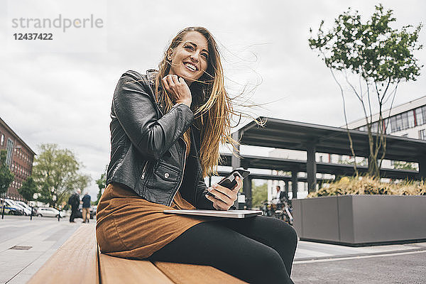 Young woman with laptop and cell phone in the city