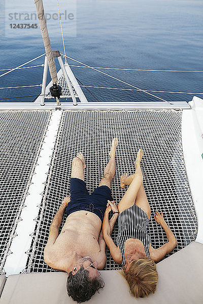 Mature couple on a sailing trip lying on trampoline  relaxing