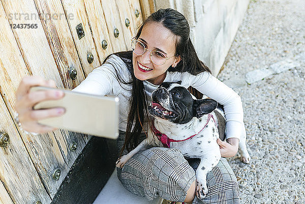 Young woman using smartphone  taking a selfie with her dog