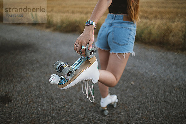 Young woman with roller skates on country road  partial view
