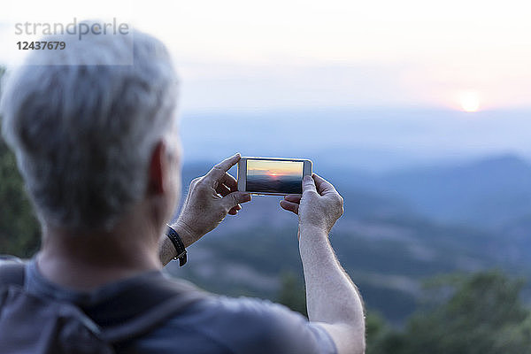 Spain  Catalonia  Man taking pictures of Montserrat at sunset