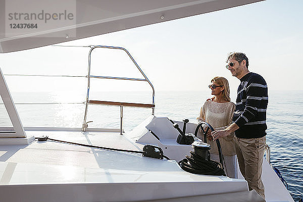Mature couple navigating catamaran on a sailing trip