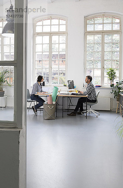 Colleagues working at desk in a loft office