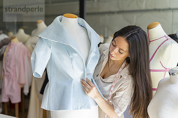 Young fashion designer fitting clothes on dressmaker's model