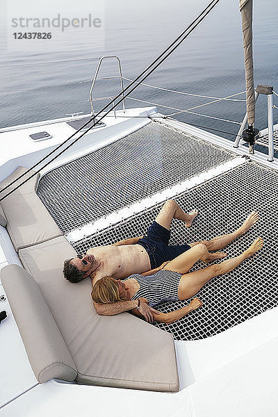 Mature couple on a sailing trip lying on trampoline  relaxing