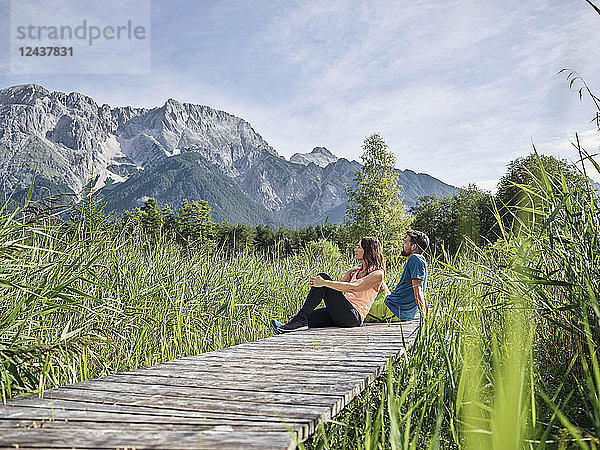 Austria  Tyrol  Mieming  couple resting on a boardwalk in the mountains